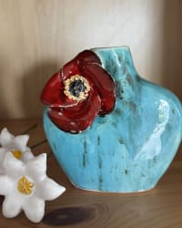Side view of turquoise vase showing the sculpted red flower against the glaze