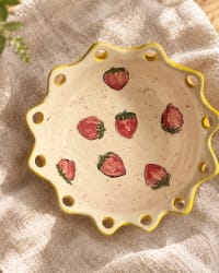 Handmade cream ceramic bowl with painted strawberries and a yellow scalloped rim.