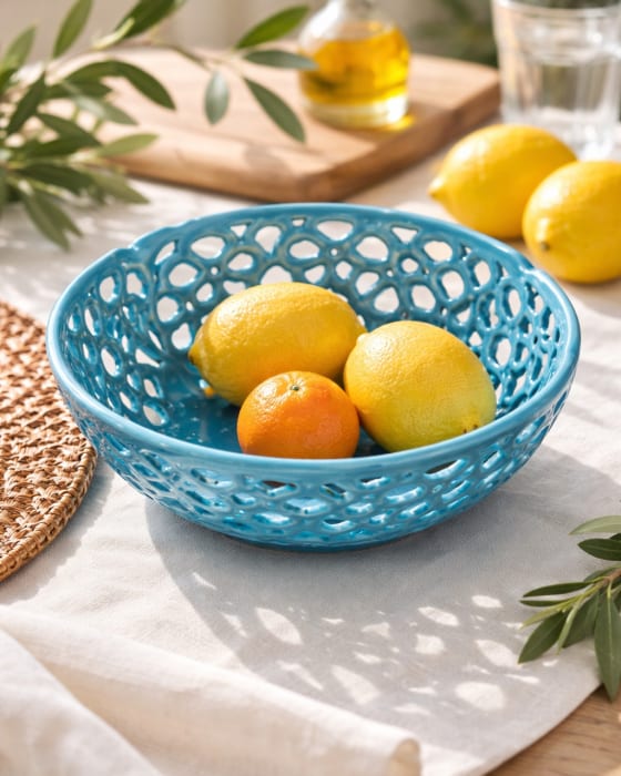 Turquoise blue ceramic fruit bowl with intricate openwork floral design and vibrant glossy glaze