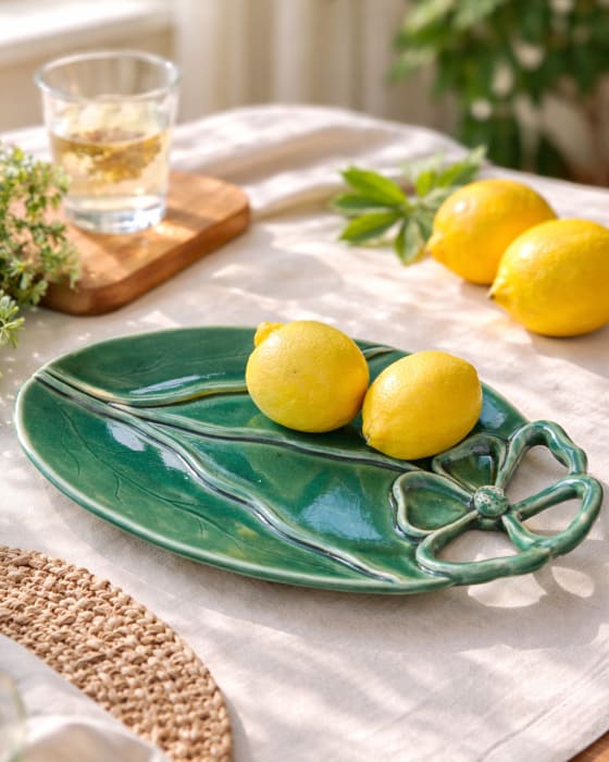 Emerald green ceramic leaf-shaped platter with sculpted floral handle and glossy glazed finish