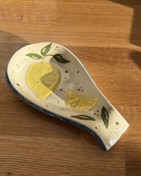 Handmade ceramic lemon spoon rest with hand-painted yellow lemons and green leaves. A colourful pottery kitchen accessory and unique handmade gift.