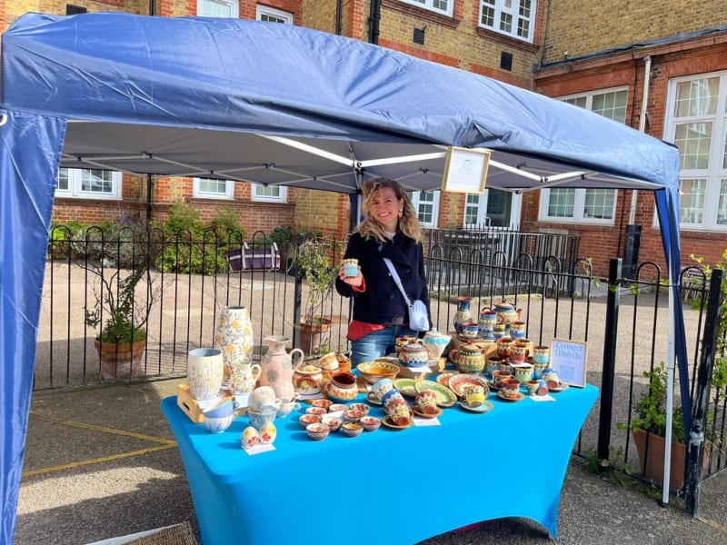 InchyArt handmade ceramics displayed at an artisan market stall with risers and wooden crates