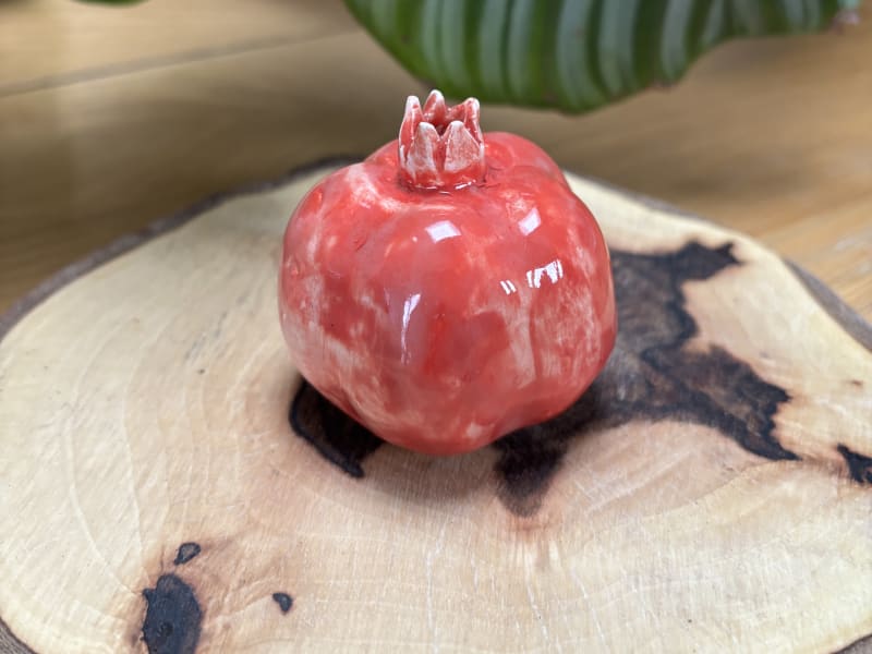 A handmade coral-red ceramic pomegranate from InchyArt, a symbol of love, abundance and new beginnings