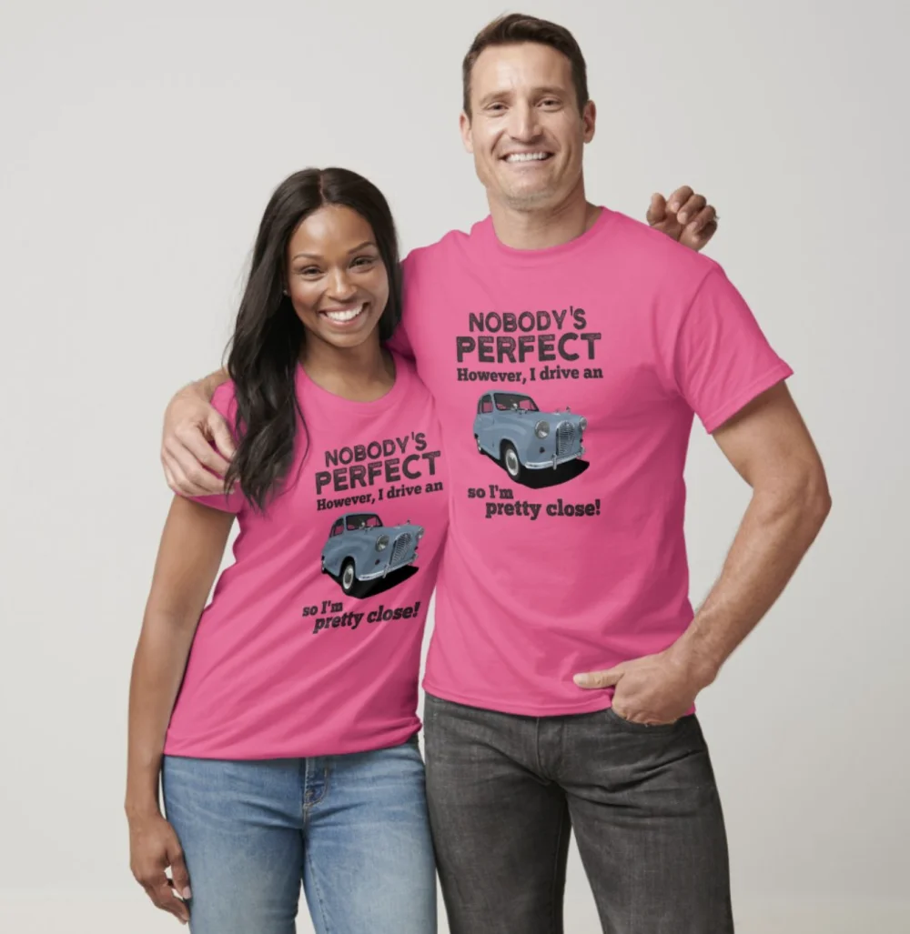A couple, a woman and a man, both wearing bright pink t-shirts with the text 'Nobody's perfect, however, I drive an A35 so I'm pretty close!' and an illustration of an A35.