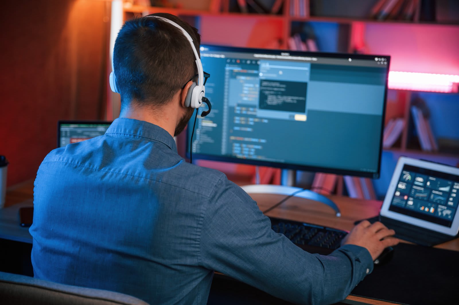 Infrastructure engineer reviewing systems across multiple monitors with a headset