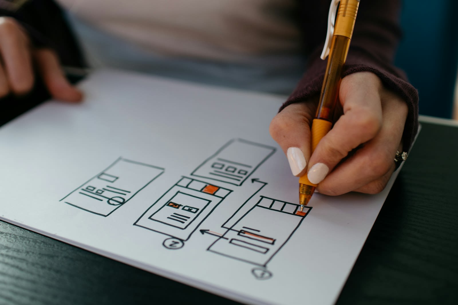 UX designer sketching mobile app wireframes and user flows on paper