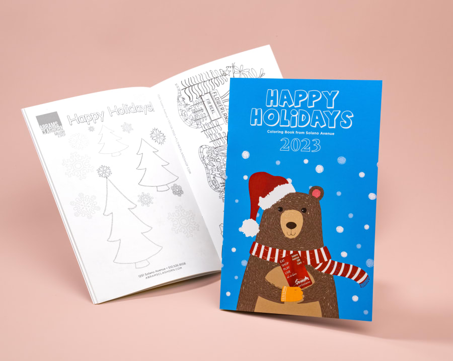 Happy Holidays coloring book with open blank coloring book in background