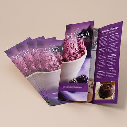 pile of Mora Creamery restaurant brochures with one open brochure