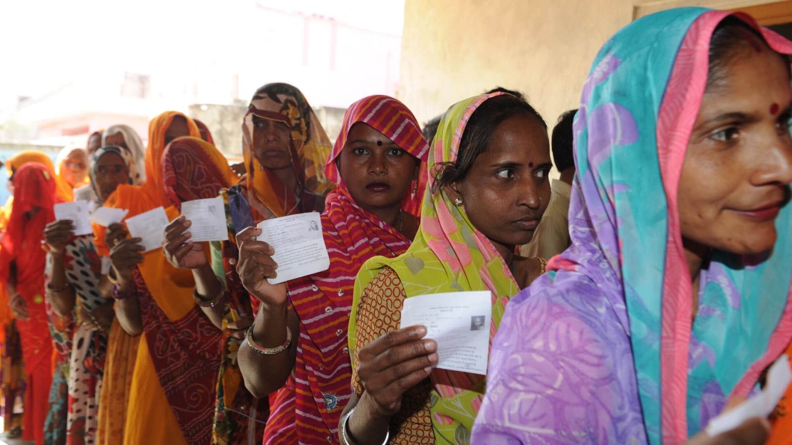 voters standing in a queue showing voter cards (file image)