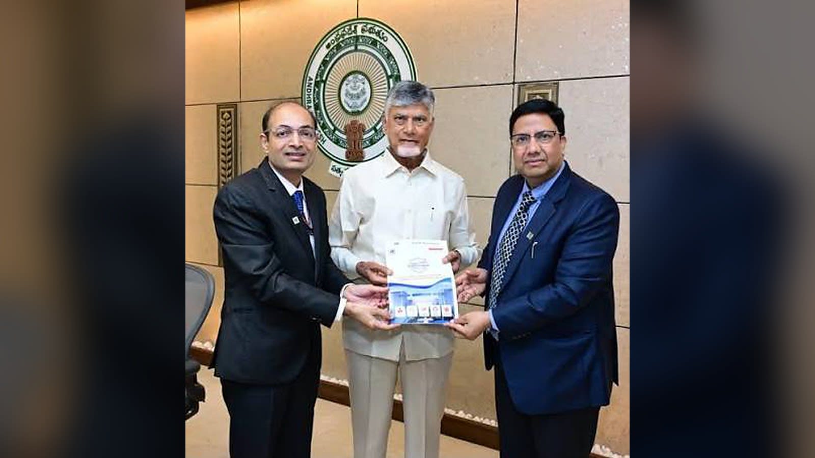 The PanIIT Andhra Pradesh Summit 2026 brochure being presented in front of the Andhra Pradesh government emblem