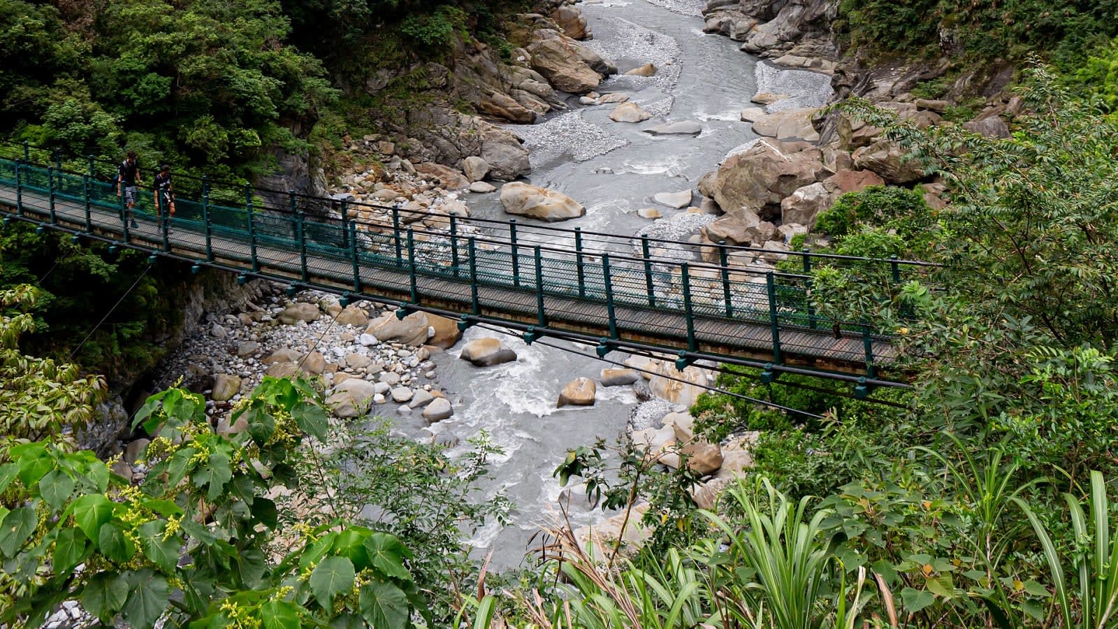 flooded mountain river valley with damaged suspension bridge (file image)