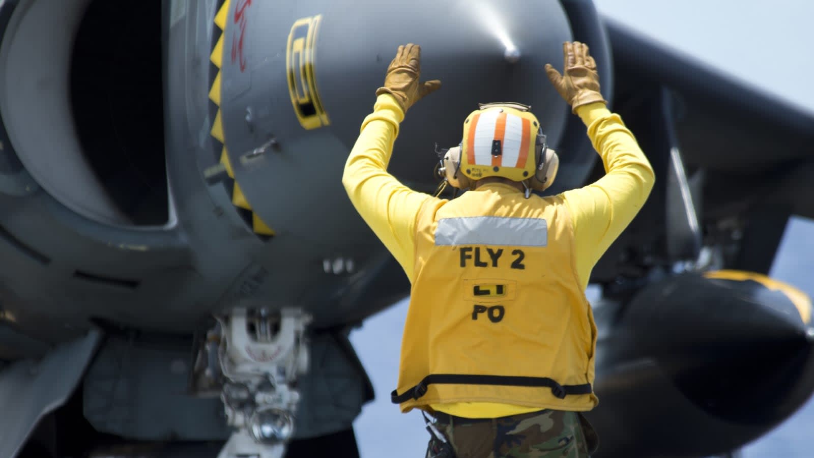 US Navy crew directs Harrier jet on warship flight deck