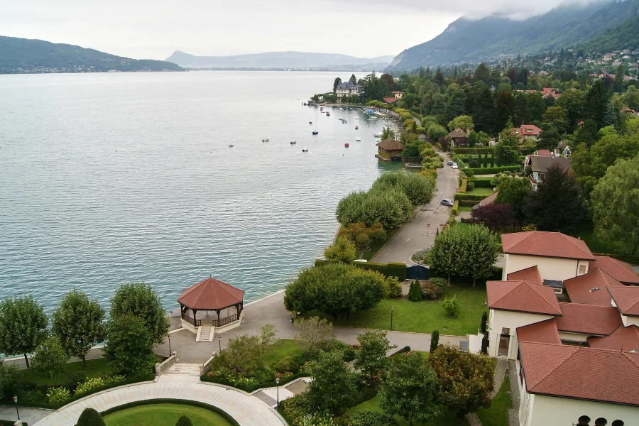 Vue du lac d'Annecy en hauteur avec des habitations et des espaces verts au bord de celui-ci