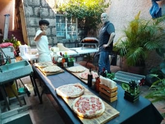 Invitados disfrutando barra de pizza en fiesta