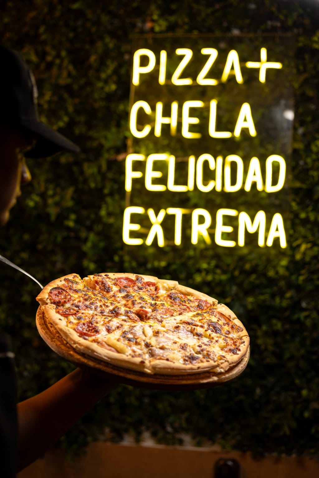 Letrero de neón «Pizza + chela, felicidad extrema» y una pizza de Yardis