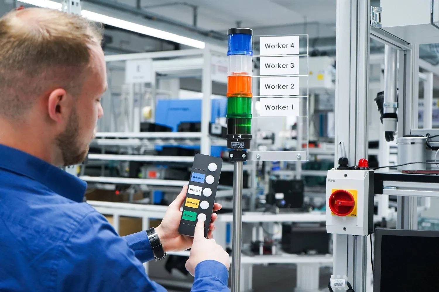 Factory floor with wireless andon system displaying real-time alerts on LED board while operators respond to production issues quickly