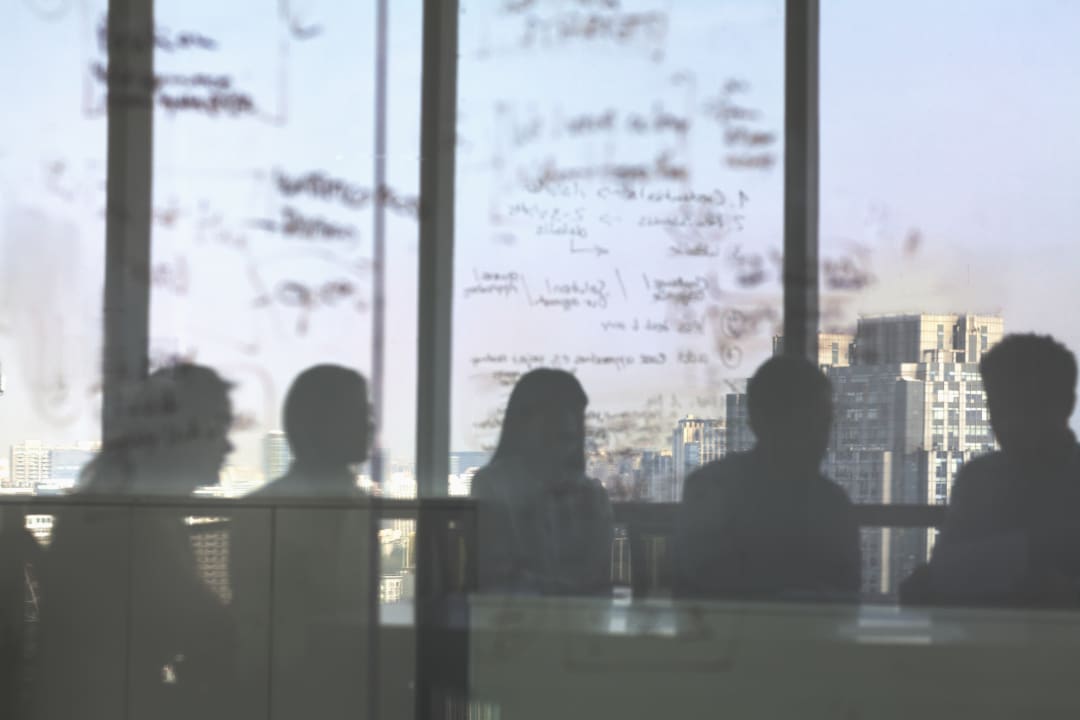 Individuals in office seen through clouded glass with writing on it