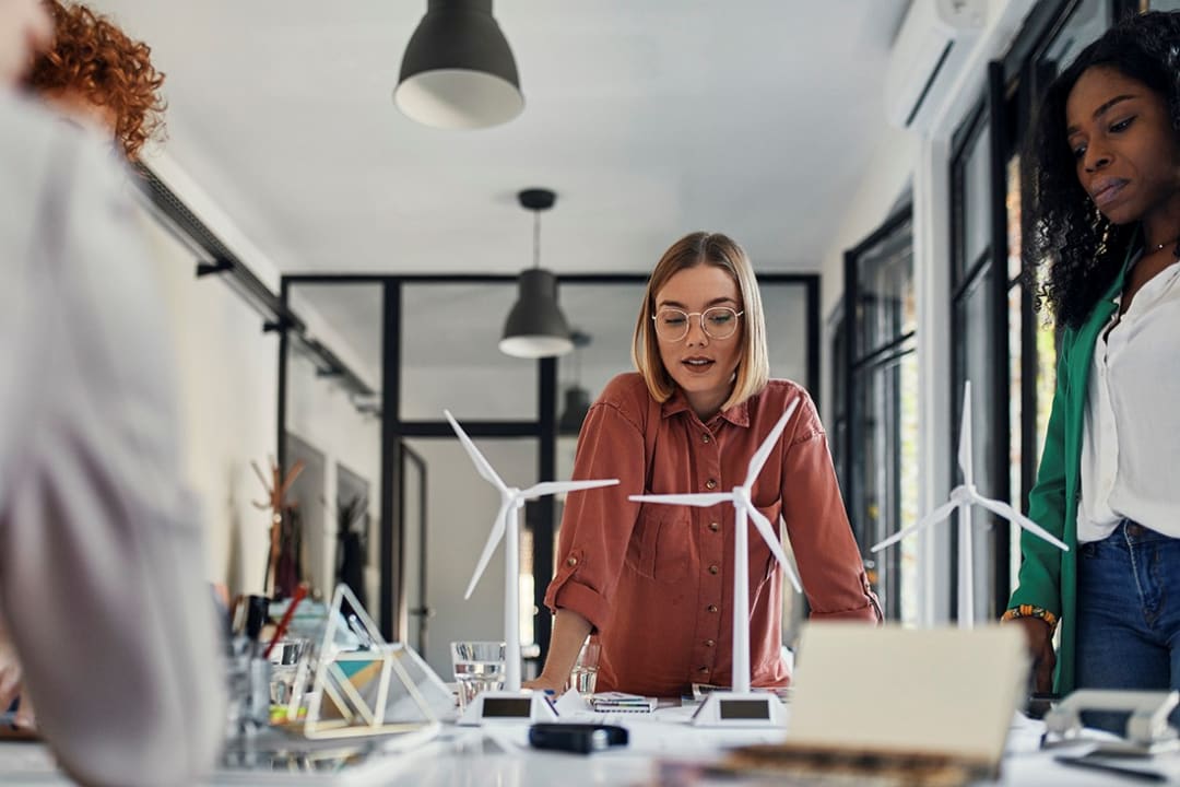 Early career professionals discuss work over a site model.