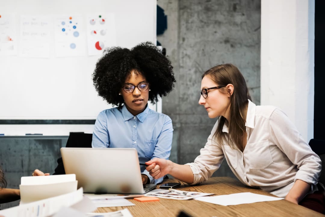 Two women sitting in a business meeting in a modern office.