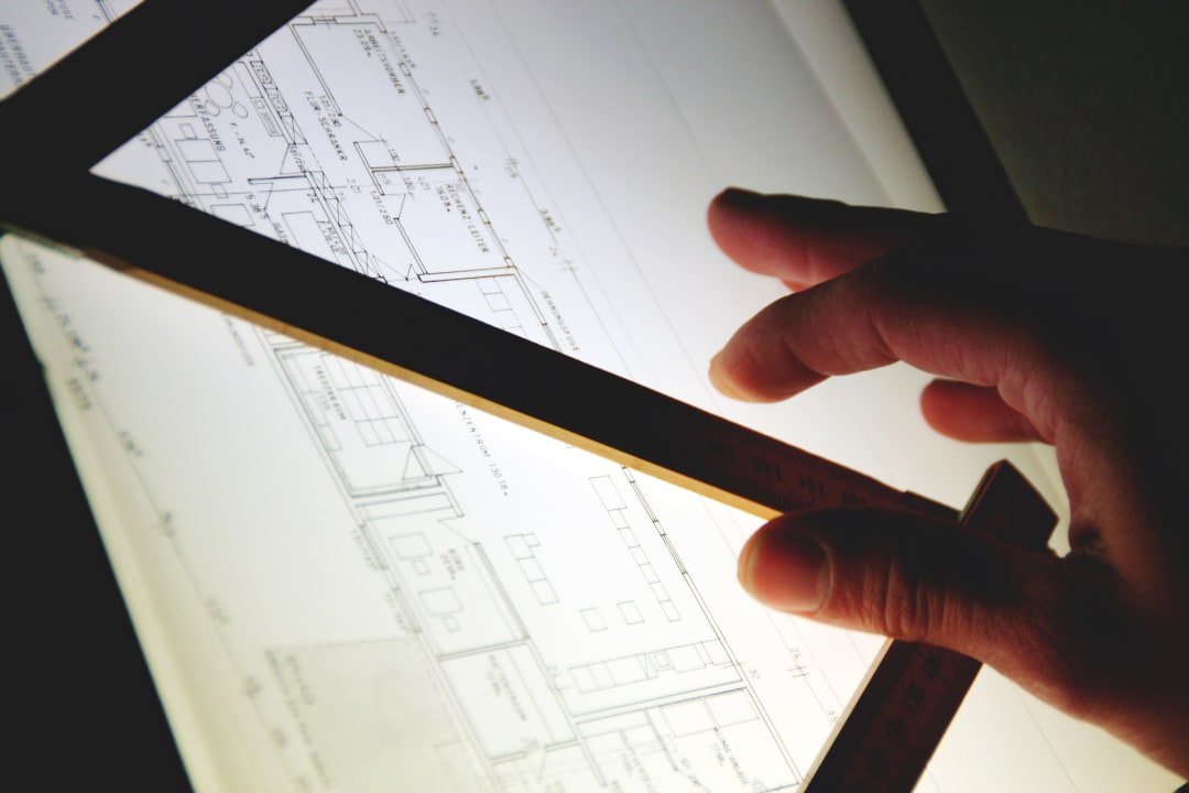 Lightbox with architectural plans, straight edge and architect's hand