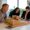 three people looking at building model