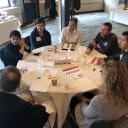 Group of eight professionals sitting at a round table discussing philanthropic opportunities for architecture firms