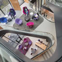A Winding stair from above with a series of seating areas on the landings with purple and magenta chairs.