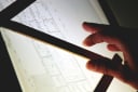 Lightbox with architectural plans, straight edge and architect's hand