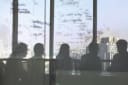Individuals in office seen through clouded glass with writing on it