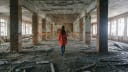 Unrecognizable woman in a red cloak inspects destroyed building after the disaster earthquake, flood, fire. stock photo