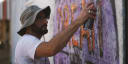 man spray painting the word "dream" on a concrete wall