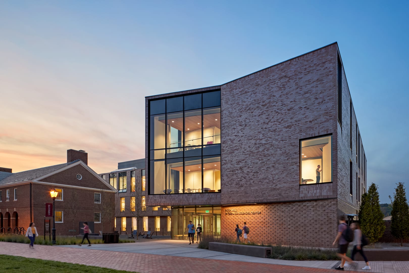 The front face of a campus science building. It's exterior marries traditional red brick architecture with large section of modern floor to ceiling windows.