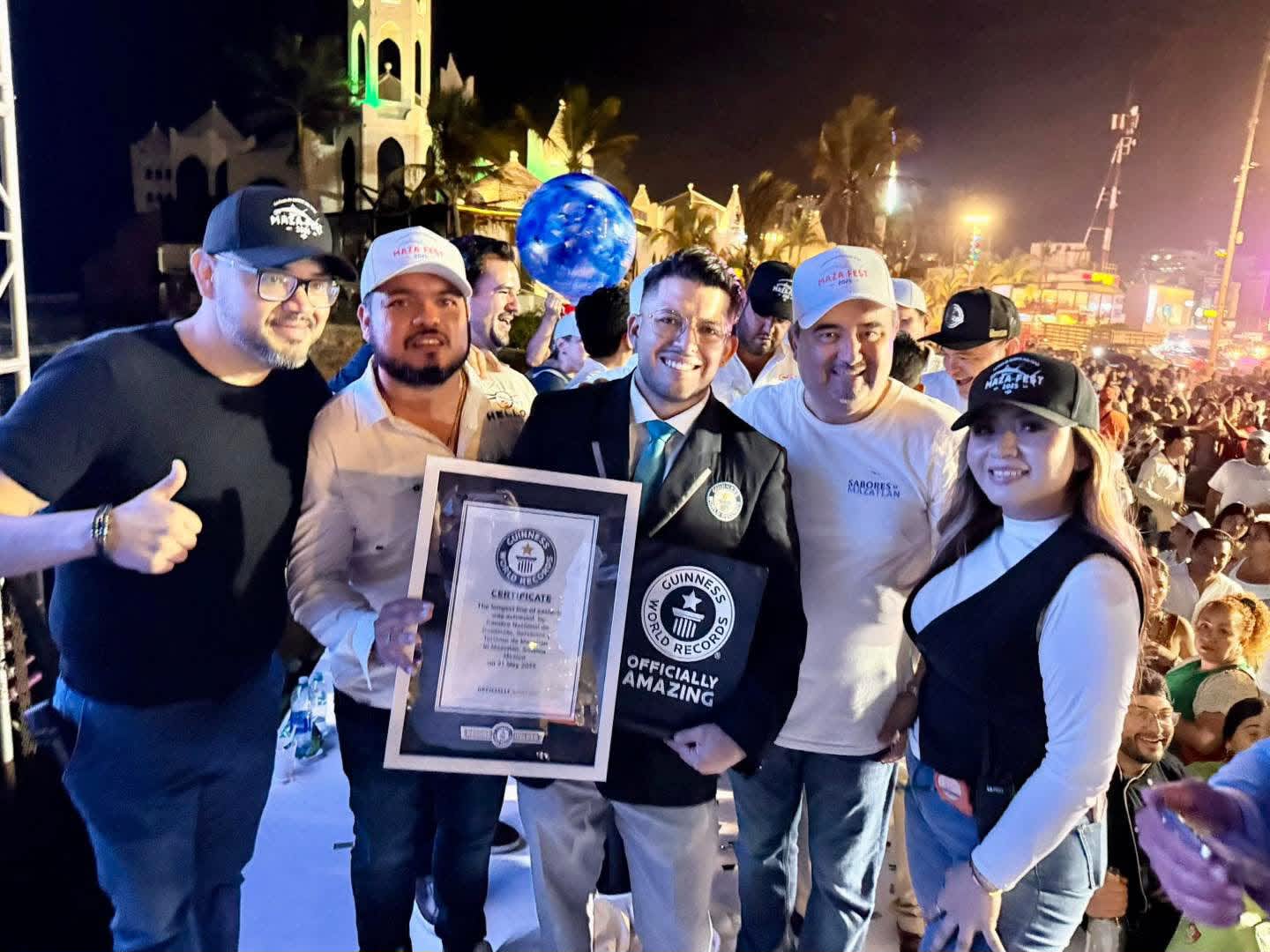 Participantes celebran junto a un representante de Guinness World Records con el certificado del récord en Mazatlán