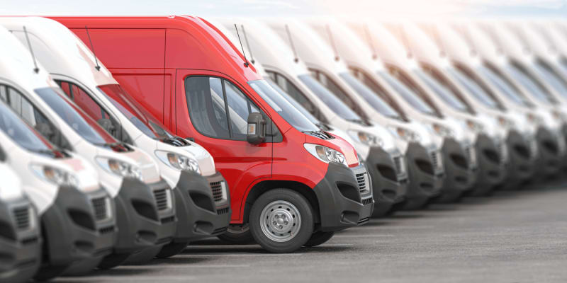 Reihe weißer Lieferwagen, einer in Rot