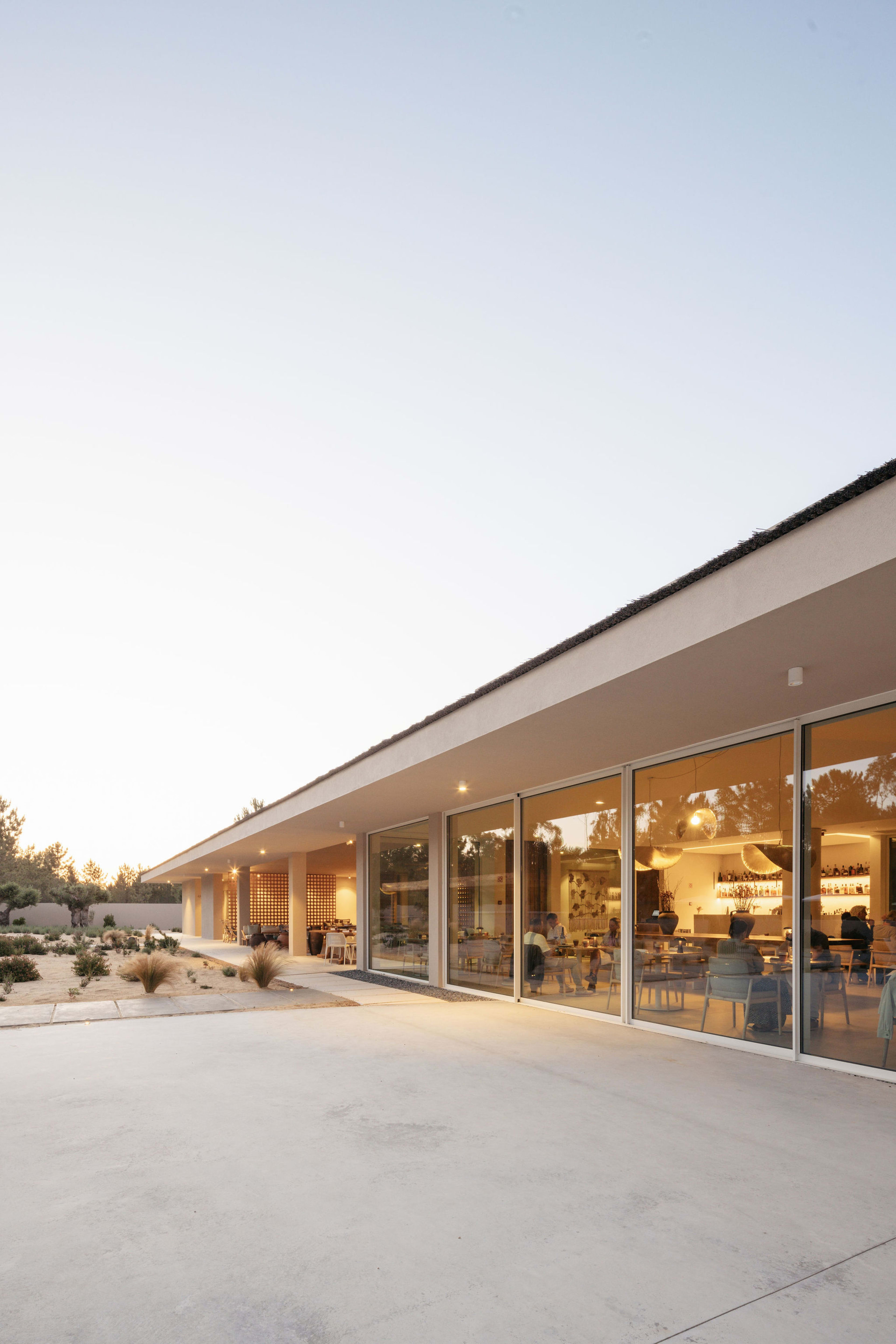 Glass facade of the Spatia Comporta clubhouse at dusk