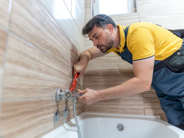 Plombier partenaire diagnostiquant un manque de pression d'eau dans une salle de bain