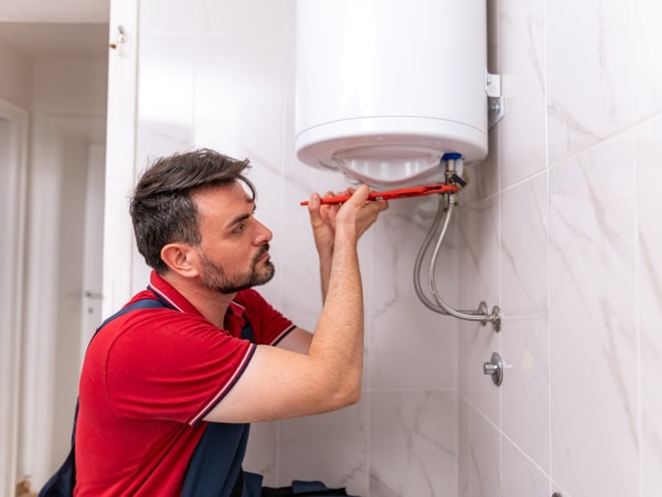 Plombier partenaire diagnostiquant une panne sur un chauffe-eau électrique