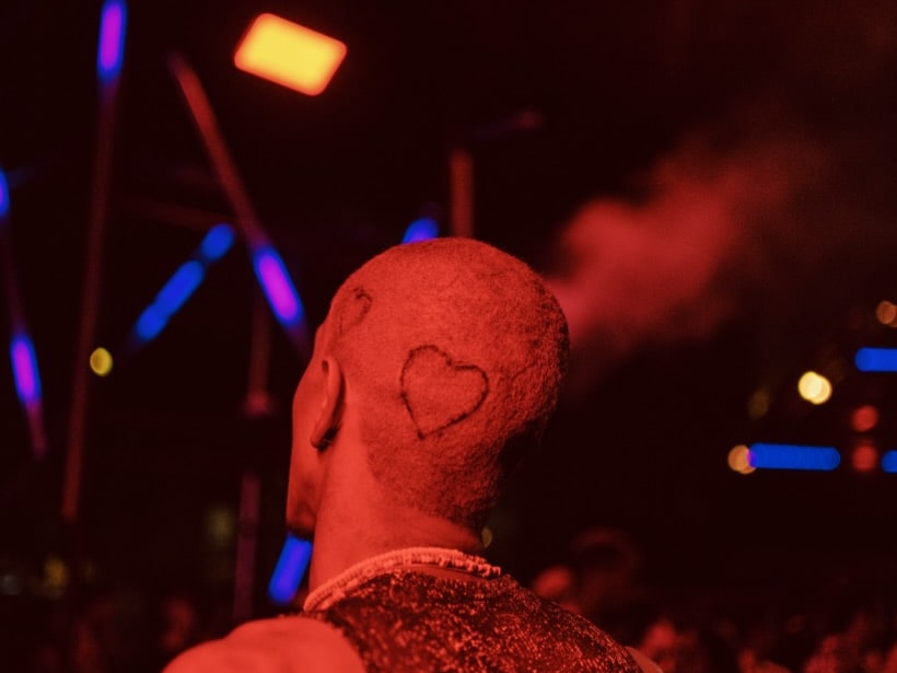 The back of a head, marked with two stars, in a dark room with a red hue.