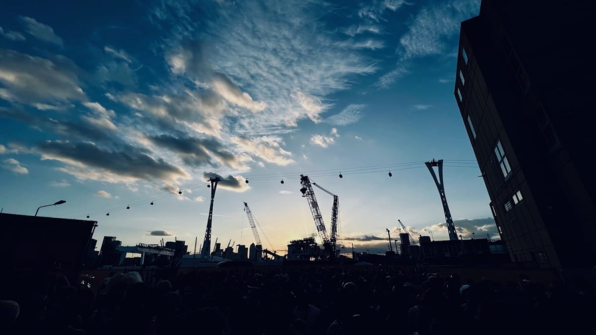 Dramatic evening sky over the Docklands with industrial cranes, viewed from Adonis club, a top gay nightlife destination in London.