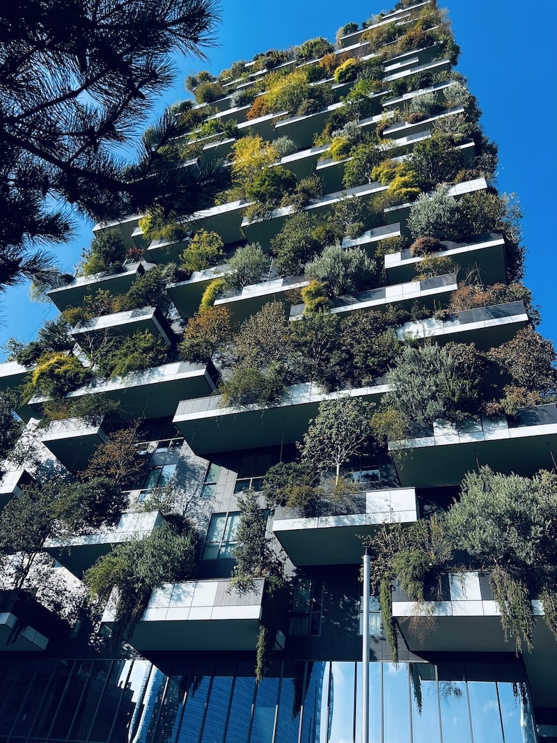 Modern residential building in Milan called Bosco Verticale, adorned with vertical gardens on each balcony, showcasing urban green architecture.