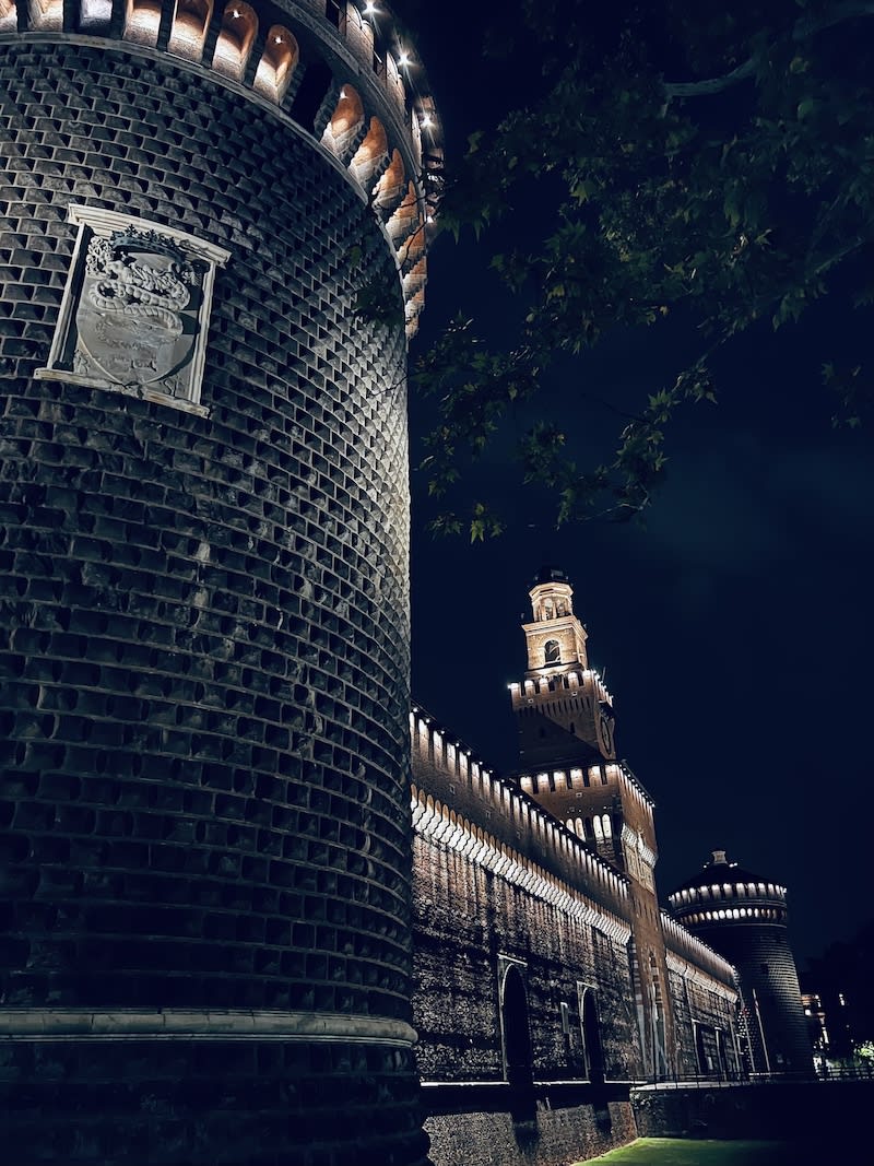 Nighttime view of the historic Castello Sforzesco in Milan, beautifully illuminated, highlighting its robust architecture.