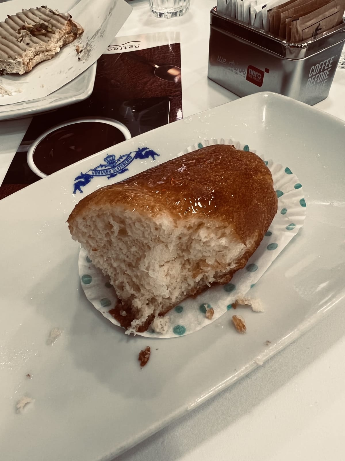 A partially eaten baba, a classic Neapolitan dessert, sits on a plate at a local pasticceria, offering a taste of the sweet traditions in gay Naples, Italy.