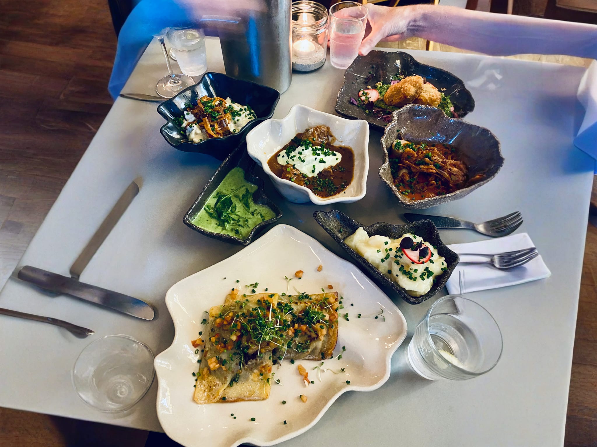Assorted German tapas served at Klinke restaurant in Berlin, featuring a variety of dishes such as creamy mashed potatoes with chive garnish, rich beef stew, and crispy fried items on artistically designed plates, capturing the essence of Berlin's culinary diversity.