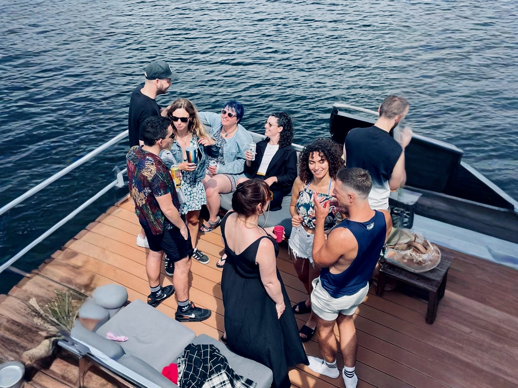 A few people chatting and having some drinks on a platform sitting on the water.
