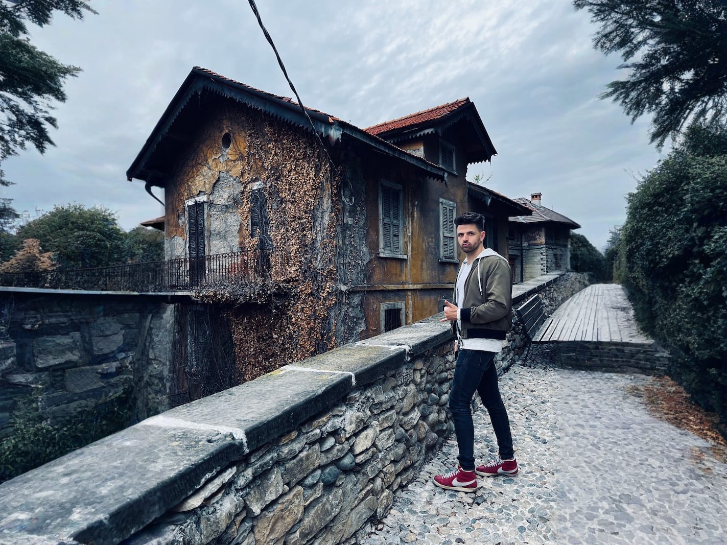 A man acting silly in front of a home in Bergamo with a dark overcast sky
