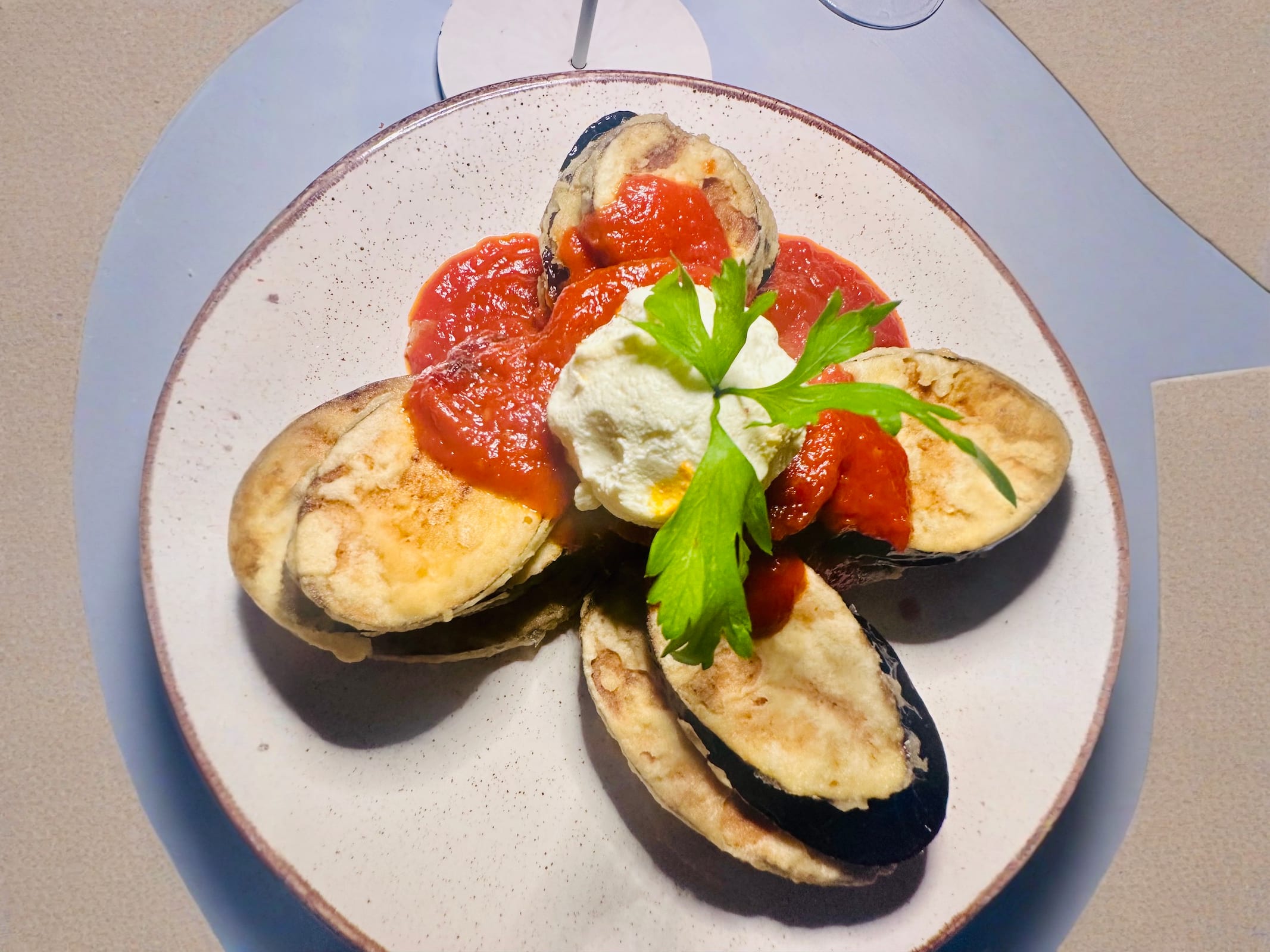 A plate of fried eggplant topped with tomato sauce and ricotta at Markakis restaurant in Paros, Greece. Savoring traditional Greek dishes is essential for what to do in Paros.