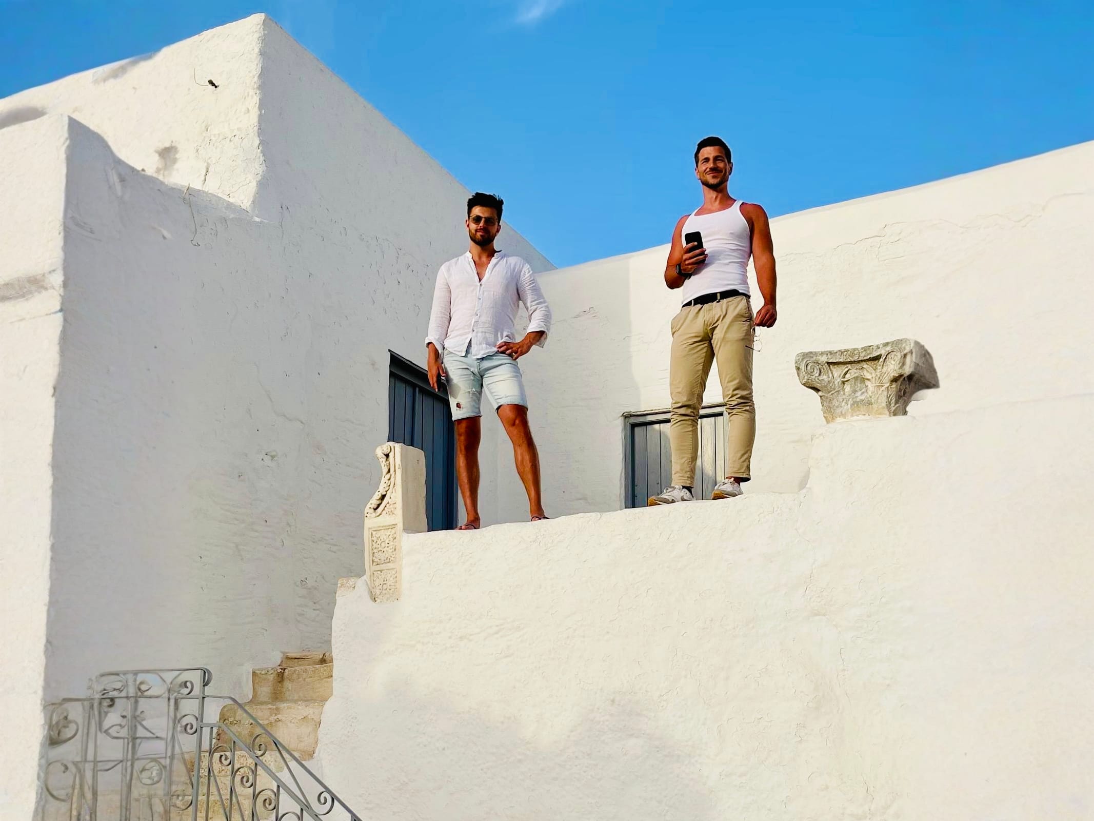 Two men standing on the rooftop of St. Antonios Monastery, Paros, enjoying the views. Visiting historical sites like this is a significant part of what to do in Paros.