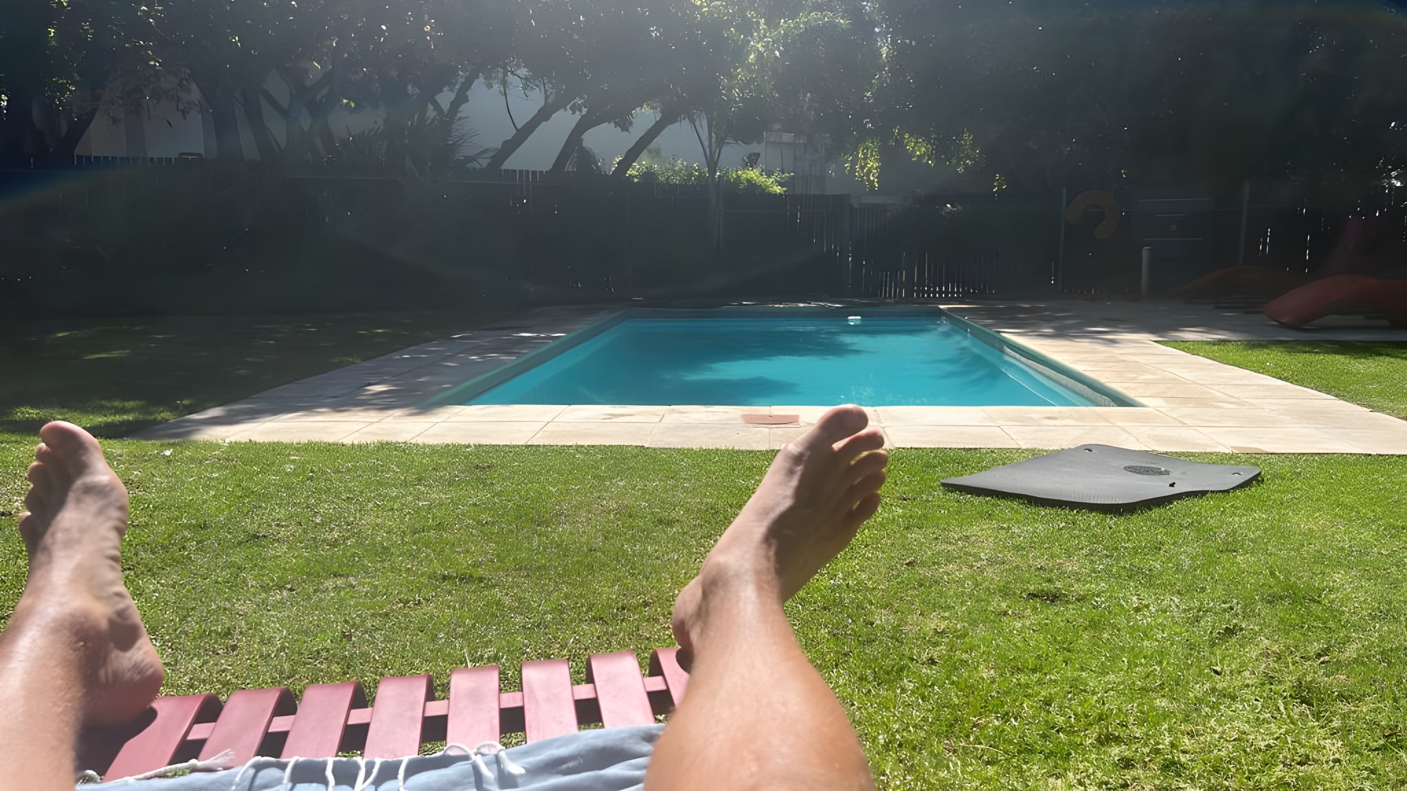 Relaxed digital nomad lifestyle depicted by a person lounging by a private swimming pool in a lush garden, typical of accommodations in Cape Town for digital nomads.