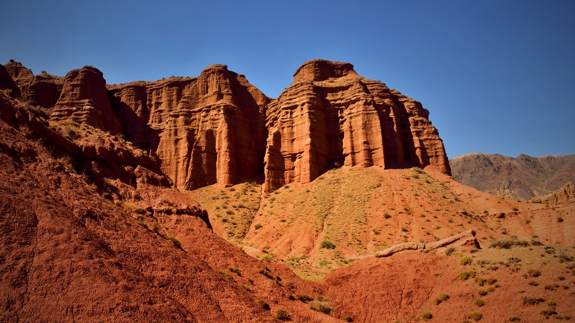 Vivid view of the red and orange cliffs of Konorchek Canyons near Bishkek, Kyrgyzstan, an ideal destination for hiking and outdoor activities.
