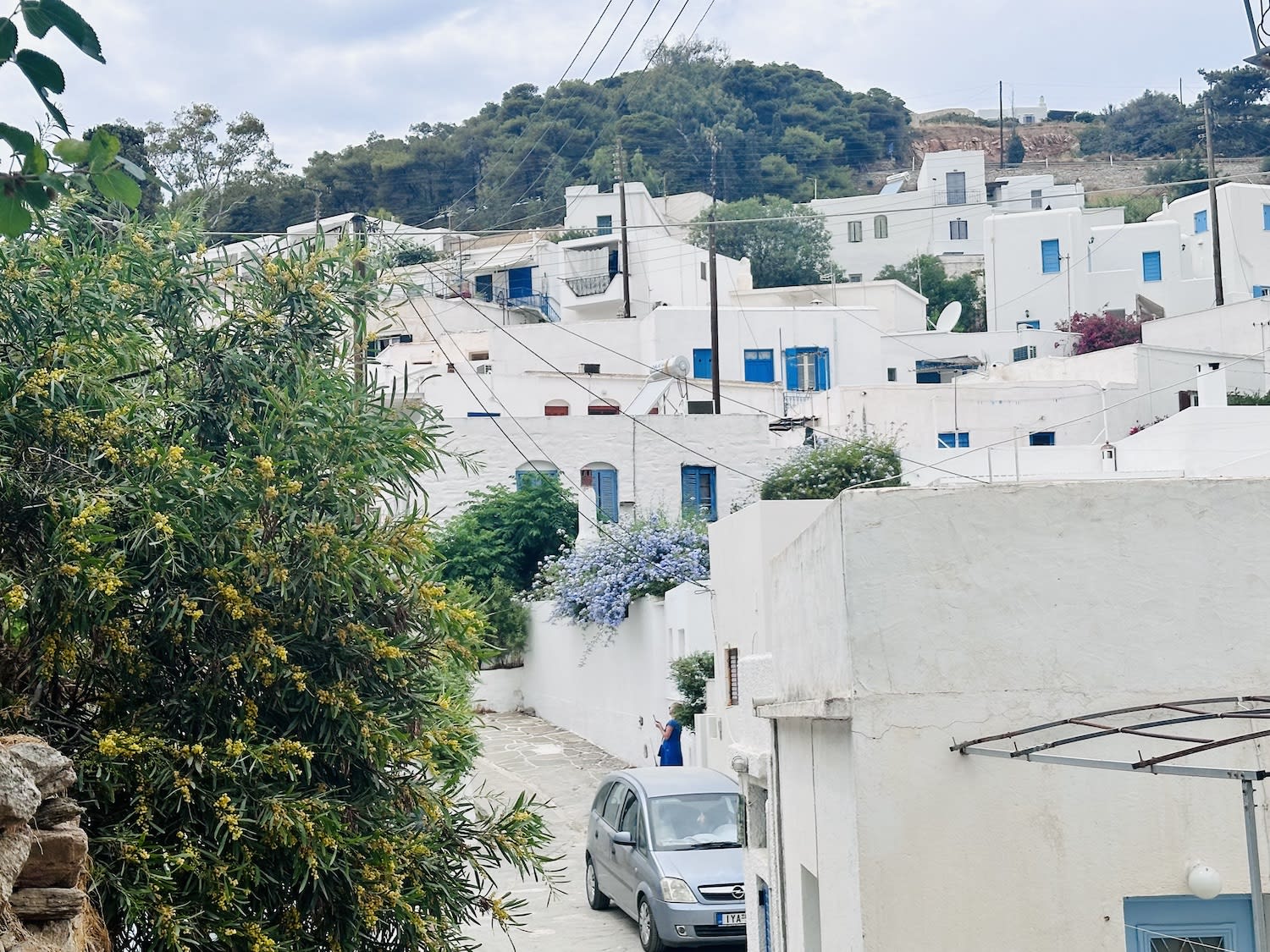 A view of the traditional village of Lefkes in Paros, Greece, featuring white houses with blue shutters nestled on a hillside. Visiting this quaint village is a highlight of what to do in Paros.